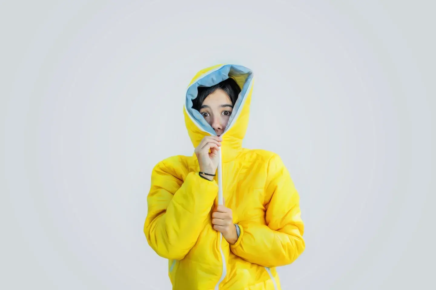 Woman with yellow jacket zipping hood over face