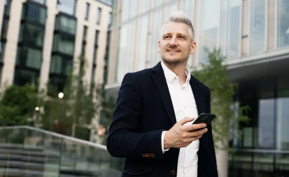 Man walking with phone and buildings in the background Man walking with phone and buildings in the background